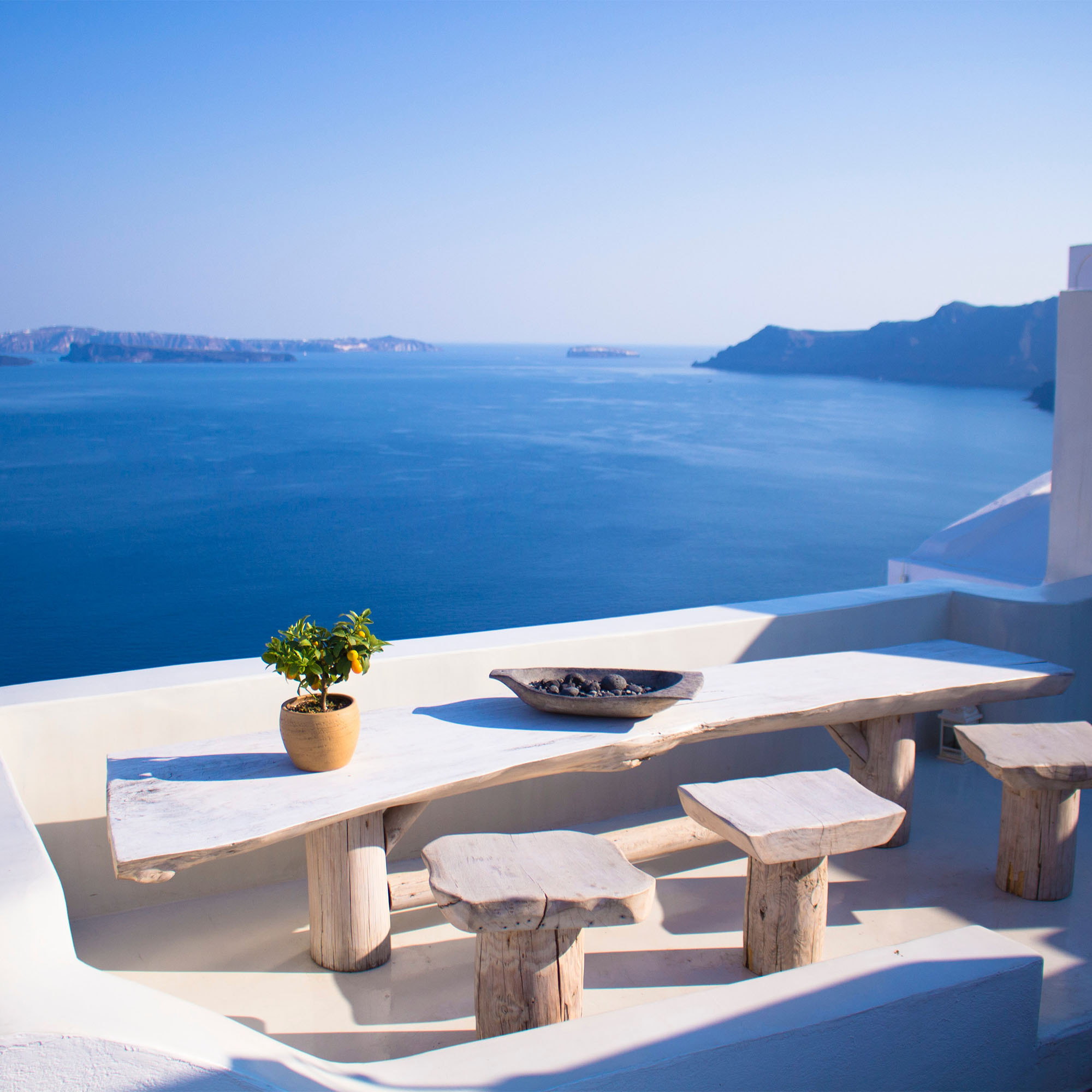 image of a rustic table and chairs overlooking the ocean in Santorini